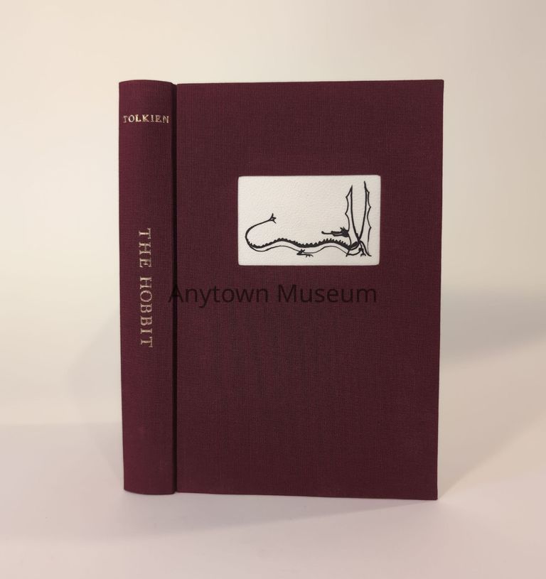 "The Hobbit" rebounding in maroon cloth featuring a dragon illustration centered in an inset panel.