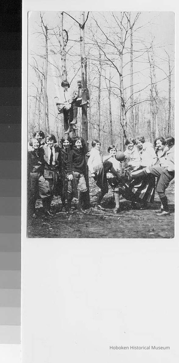 Group photo of Girl Scouts playing kickball; 2 sitting on bar between trees; no date picture number 1