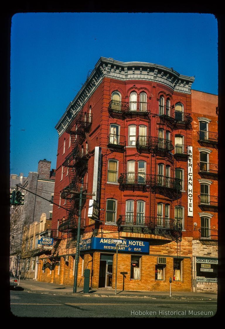 Color slide of eye-level view of front and side façades with fire escape at 76 River on the NW corner of River and Hudson Place occupied by the American Hotel picture number 1