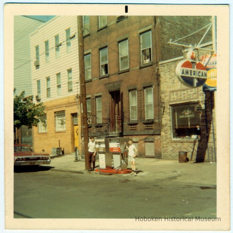 Color photo of 2 boys standing at gas pumps at Joe's Auto Repair, 219 Clinton St., Hoboken, no date, ca. 1990. picture number 1