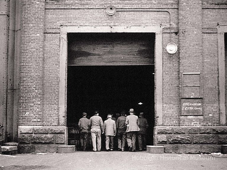 end of film as longshoremen go through open door at pier