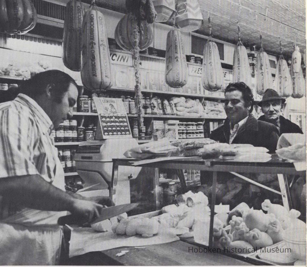 Reference image of printed photo image of interior of an Italian deli or salumeria from pg 21 of archives catalog 2002.026.0002, Hoboken, ca. 1975. picture number 1