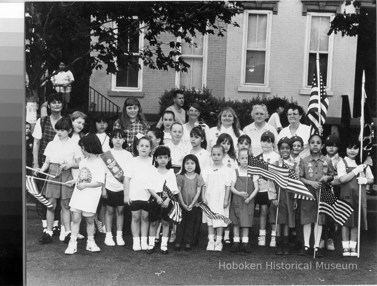 B+W group photo of of Hoboken Girl Scouts with flags standing in street, Hoboken, no date, ca. 1980-1985. picture number 1