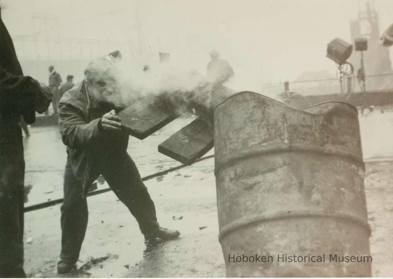 actor or extra putting wood in barrel at pier location