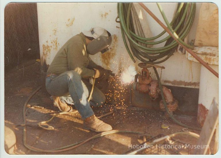 Color photo of Luis Denis using a torch on a ship at the Bethlehem Steel Shipyard, Hoboken Division, no date, ca. 1980. picture number 1