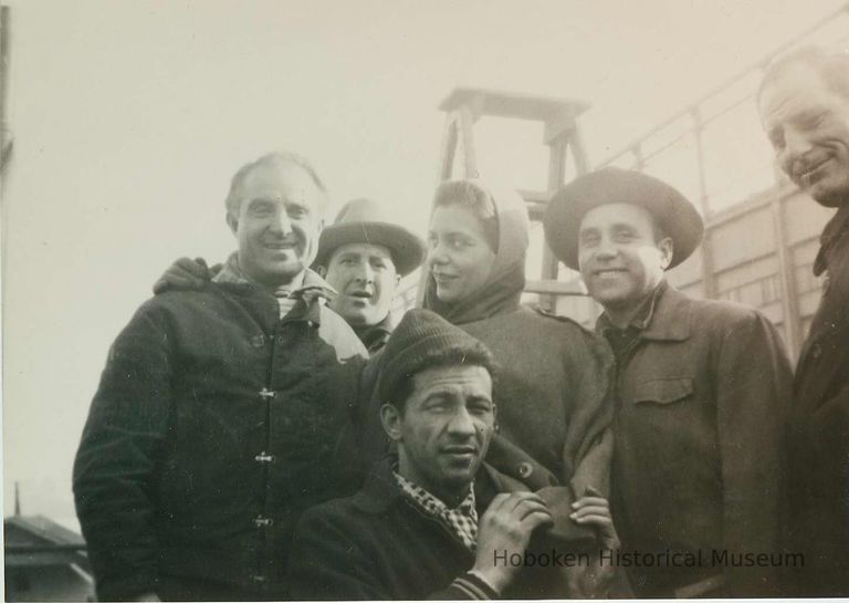 character actors or extras posed on location near Pier C; script girl?