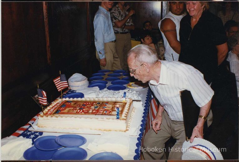 Color photo of George Kirchgessner blowing out candles on a cake celebrating 98th anniversary of United Decorating Co., Hoboken, June 27, 1997. picture number 1