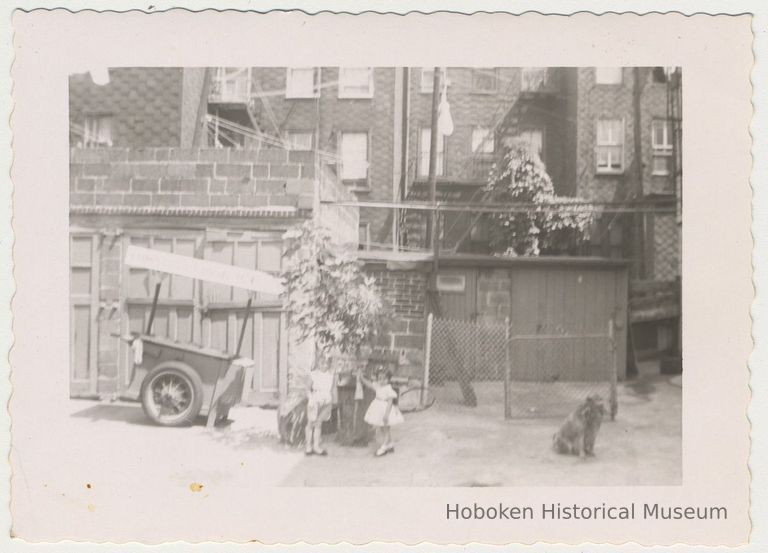 Digital image of b+w photo of Lucille Conti (left) & unknown girl in a backyard near Yum Yum cart at 416 Clinton St., Hoboken, n.d., ca. 1950s. picture number 1