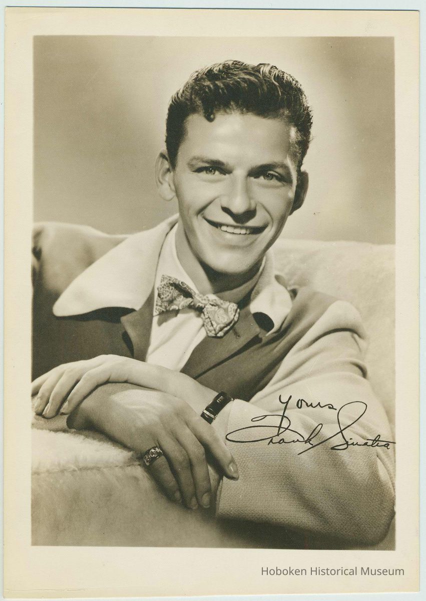 Sepia-tone textured photo of a young Frank Sinatra seated in a lounging jacket & bowtie; inscribed, signed in image, no place, no date, ca. 1939-1943. picture number 1