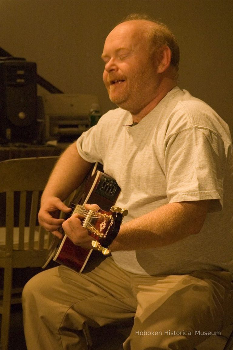 Color photos, 3, of poet Joe Weil with guitar during reading at Hoboken Historical Museum, April 23, 2006. picture number 1