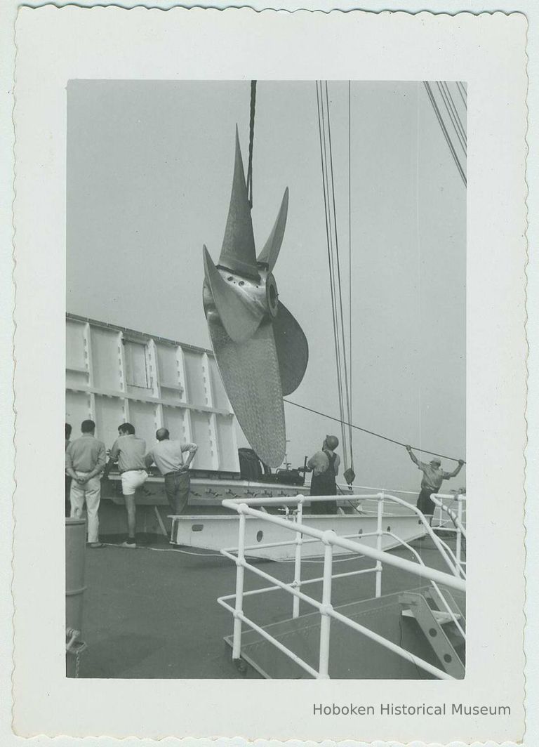 B+W photo of a 5-blade propeller being moved or placed on an upper deck of an unidentified vessel, no date, ca. 1950-1960. picture number 1