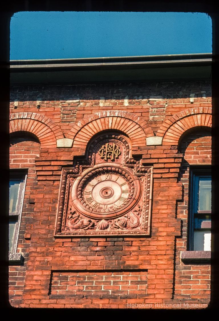 Color slide of close-up view of clockface roundel and brick arches on the facade of the Hoboken Land building at 1 Newark picture number 1