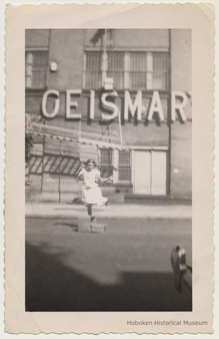 B+W photo of girl playing in 200 block of Bloomfield St. near back facade of Geismar's, Hoboken, n.d., ca. 1950s. picture number 1