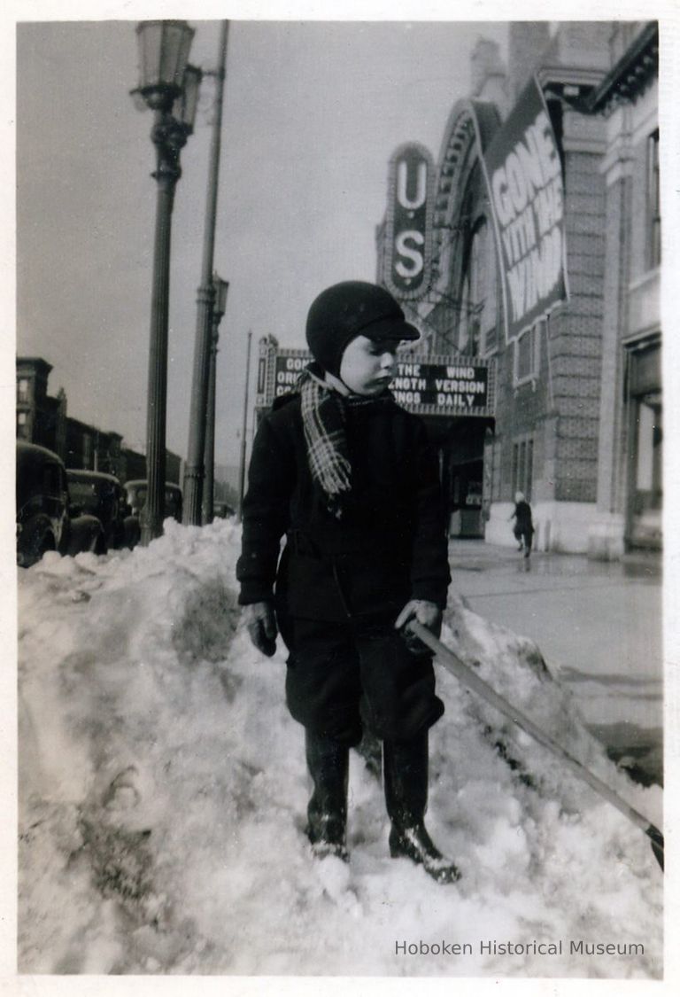 boy with snow shovel near U.S. Theater