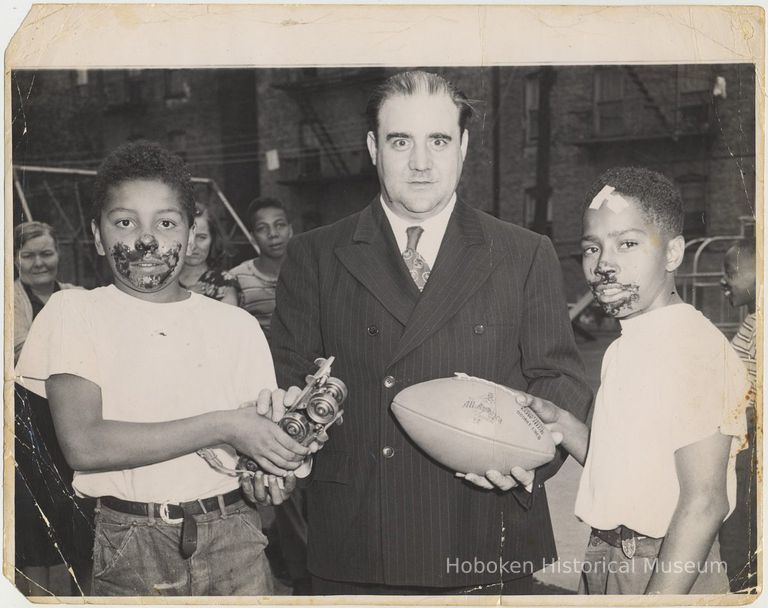 B+W photo of a man presenting prizes to 2 winners in a pie eating contest, Hoboken, no date, circa 1945-1950. picture number 1