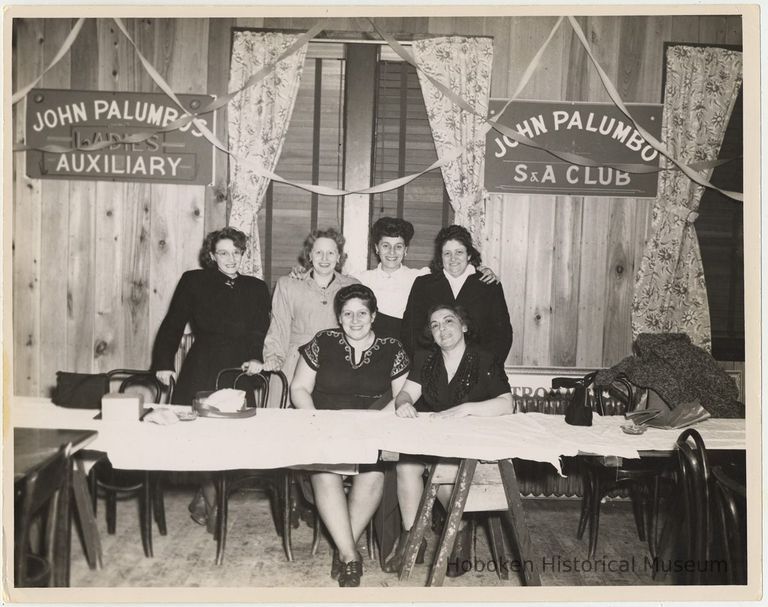 B+W photo of 6 women at trestle table with John Palumbo's Ladies Auxiliary and S.A. Club signs. picture number 1