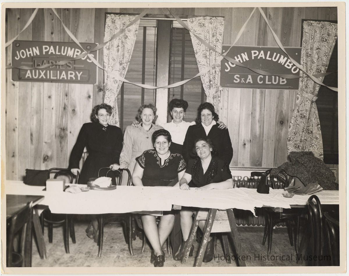 B+W photo of 6 women at trestle table with John Palumbo's Ladies Auxiliary and S.A. Club signs. picture number 1