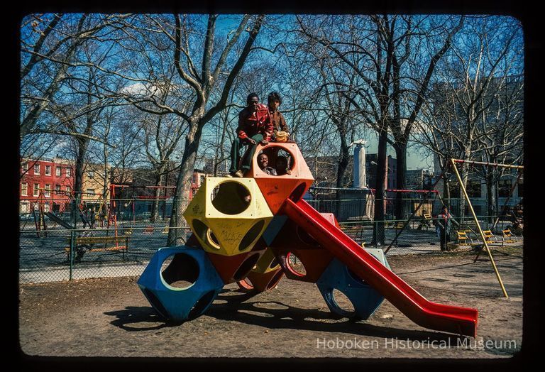 Color slide of eye-level view of children on the playground slide in Church Square Park with swing sets in the background picture number 1