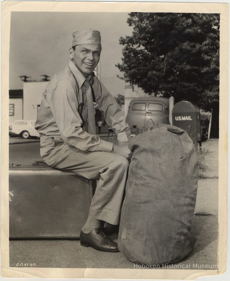 B+W publicity photo of Frank Sinatra in military uniform seated on luggage, no date, circa 1962. picture number 1