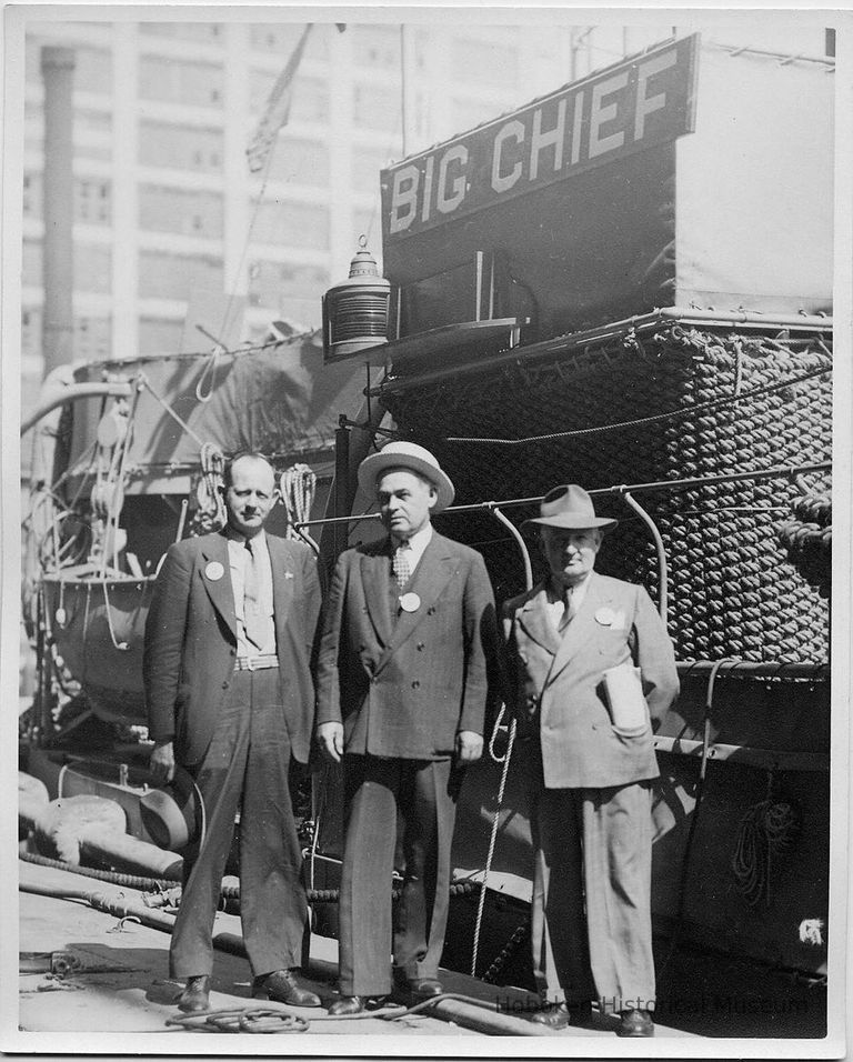 B+W photo of three men standing on dock next to vessel 