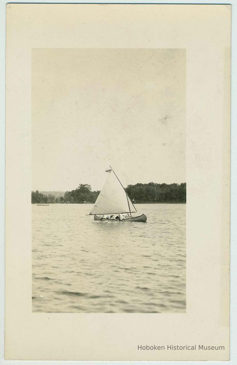 B+W photo with postcard back of a canoe with sail on a lake, no location known, no date, ca. 1940. picture number 1