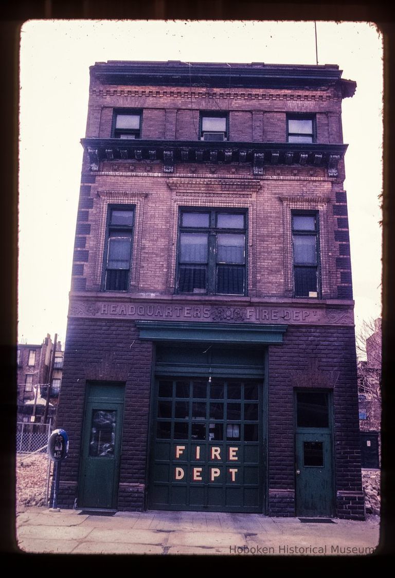 Color slide of eye-level view of fire station façade, cornice, quoins and frieze reading 