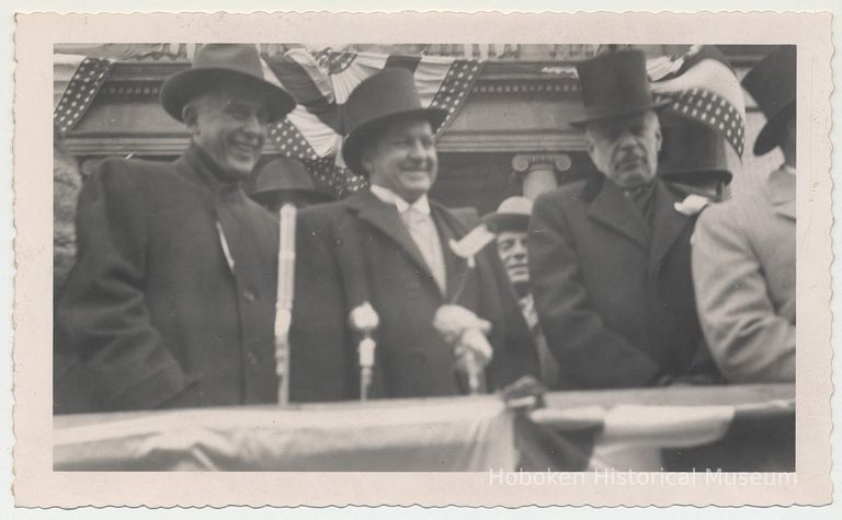 B+W photo of Mayor John J. Grogan (center) & 2 men on reviewing stand, Hoboken City Hall, Hoboken Centennial Parade, March 27, 1955. picture number 1