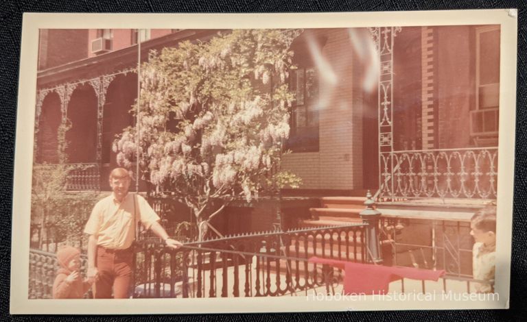 Man and child in front of 68 10th Street wisteria espalier.