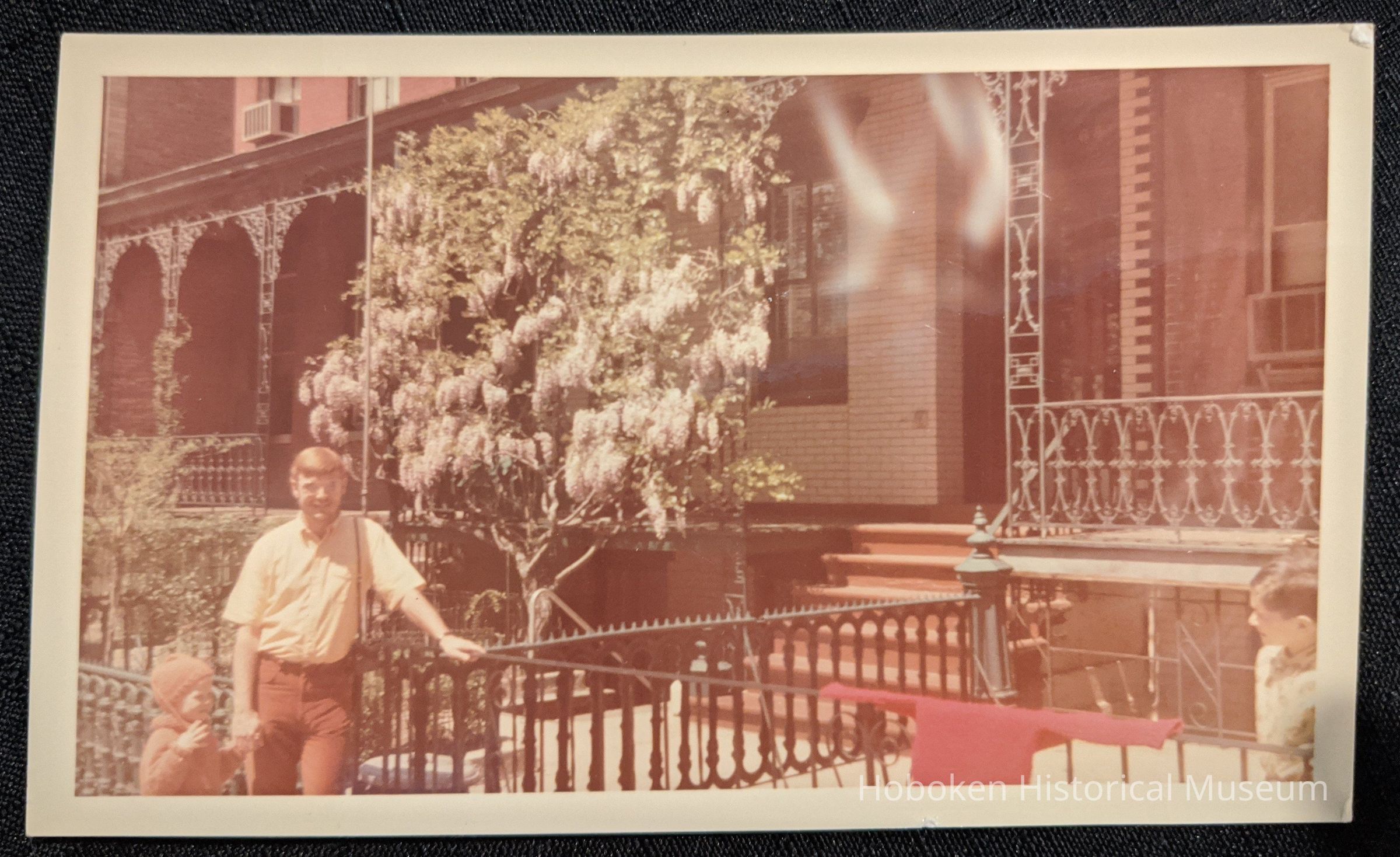 Man and child in front of 68 10th Street wisteria espalier.