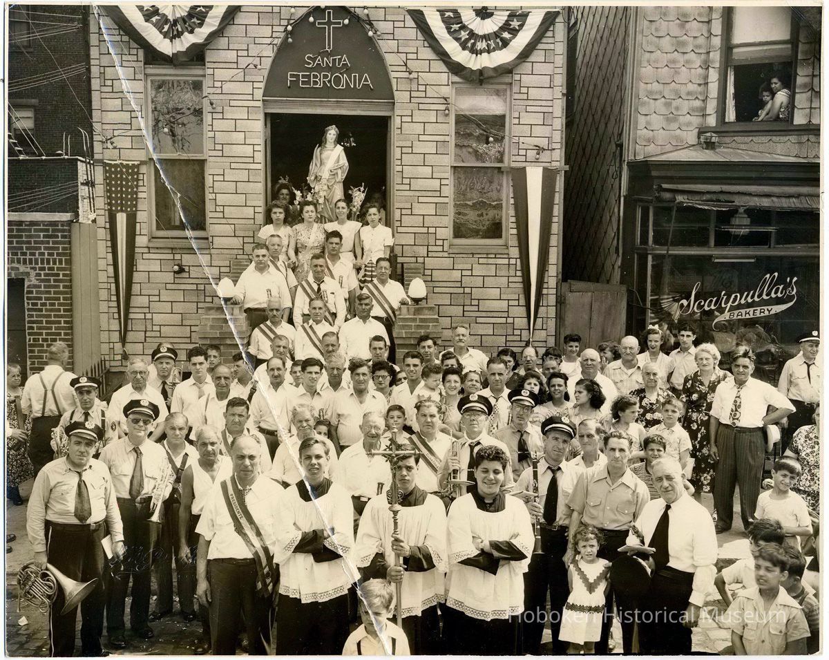 Sepia-tone photo of the exterior of Santa Febronia Society during a pageant with large assembly of people, Hoboken, no date, ca. 1940-50. picture number 1