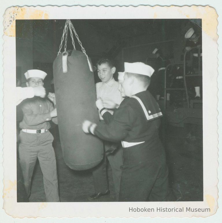 B+W photo of boys, some in sailors' uniforms, punching a heavy bag in an unidentified gym, Hoboken, no date, ca. 1940-1945. picture number 1