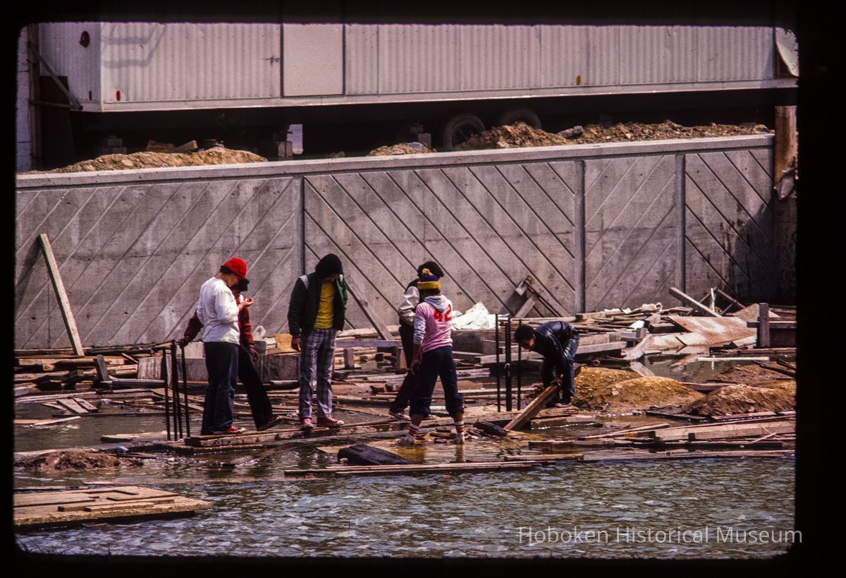 Color slide of eye-level view of six people sorting through debris at an unidentified location on the block bordered by Hudson, River, 1st and 2nd picture number 1