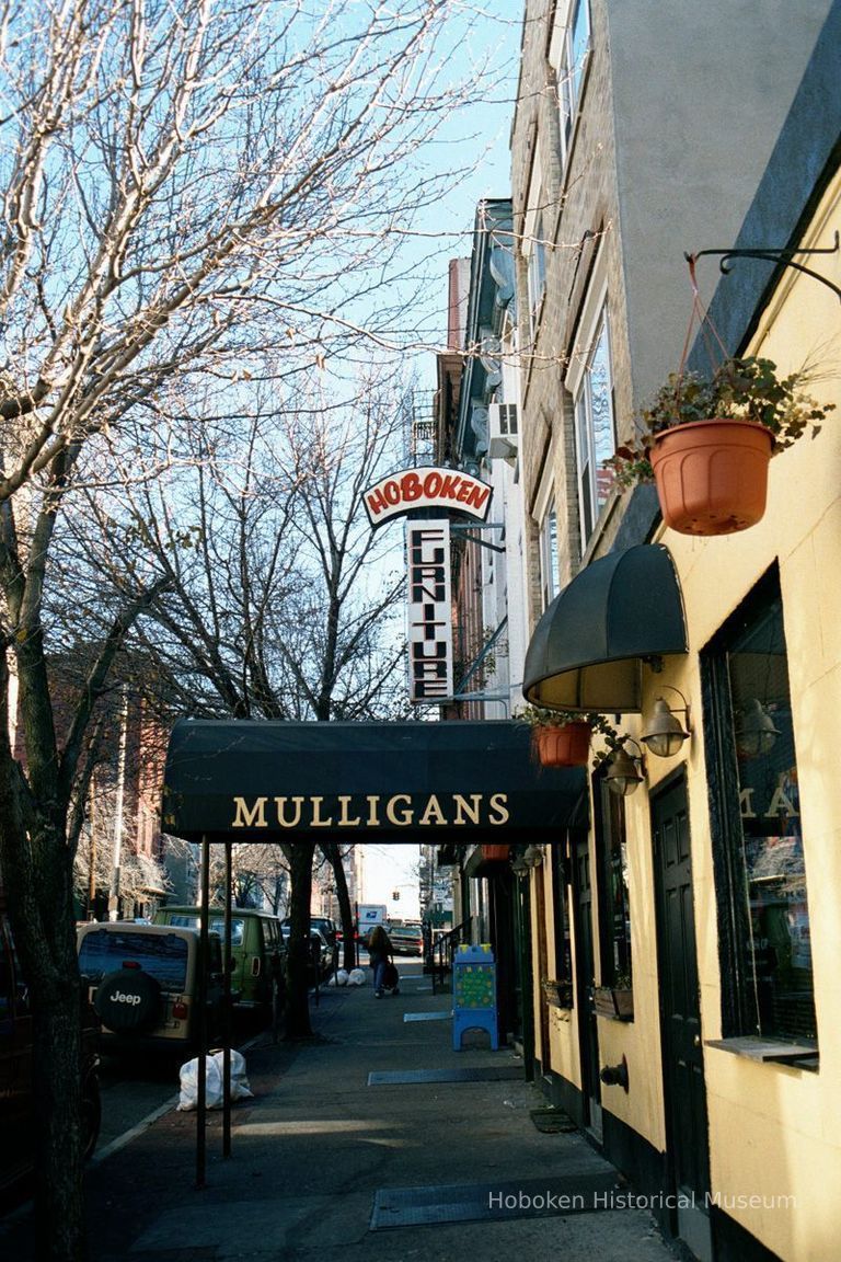 Color photo of hanging sign for Hoboken Furniture, 157 First St. and a canvas marquee for Mulligans Bar, 159 First St., Hoboken, Jan. 3 & 4, 2002 picture number 1