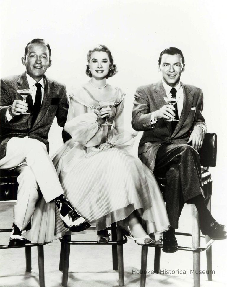 Black-and-white photo, movie still, of Frank Sinatra, Bing Crosby & Grace Kelly posed on bar stools, film 