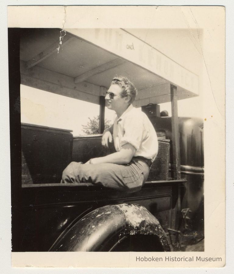 Digital image of b+w photo of Mike Conti seated in back of Lemon Ice & Yum Yum truck at 416 Clinton St., Hoboken, n.d., ca.1950s. picture number 1