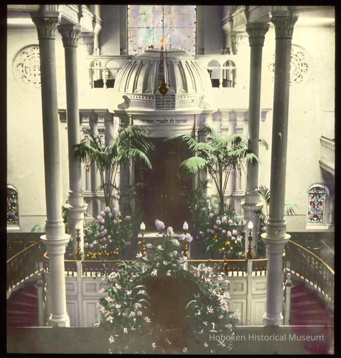Lantern slide, color, of a synagogue interior with floral decorations, used for promotional display in Hoboken, no date, ca. 1920. picture number 1