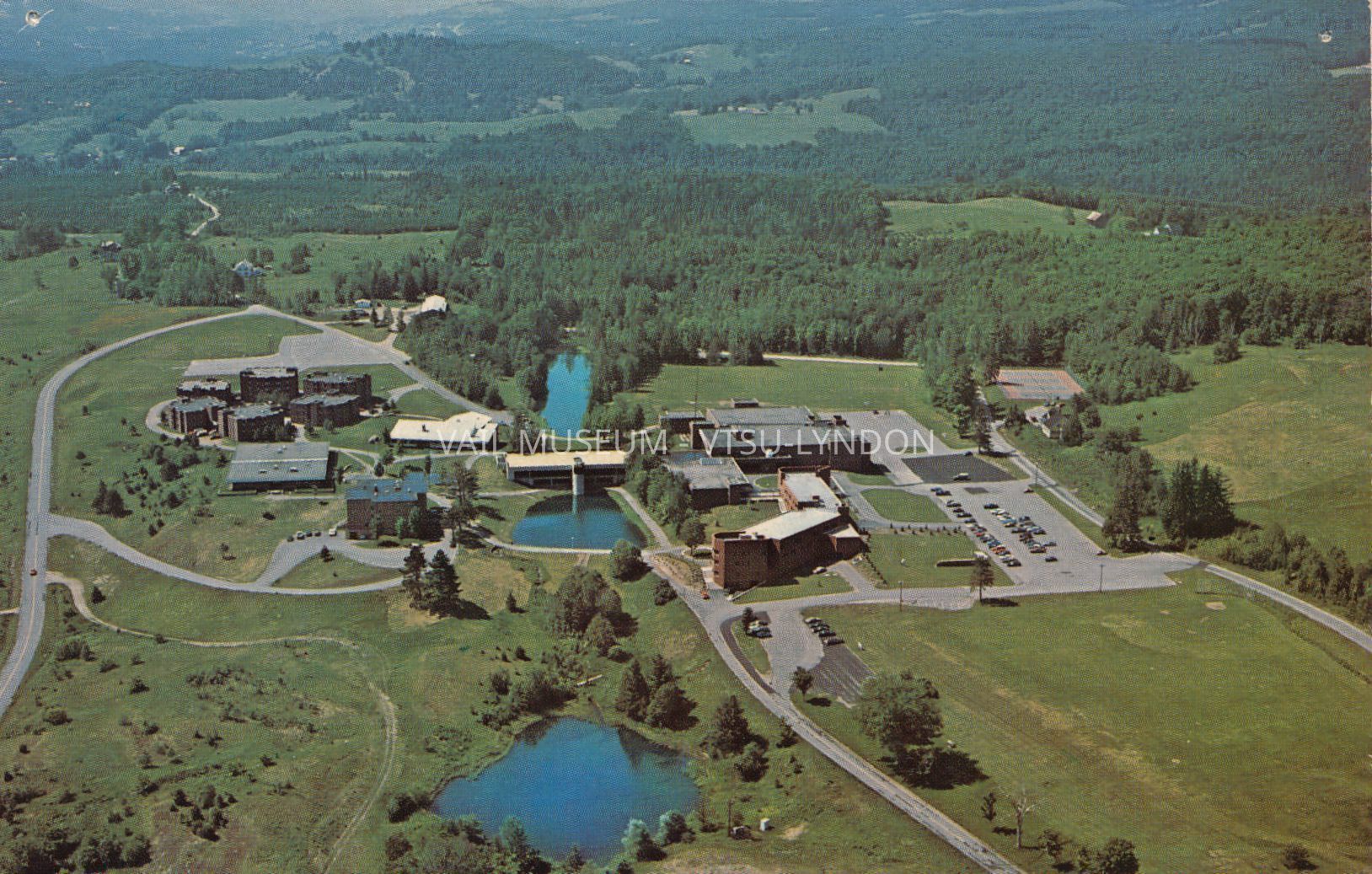 Aerial real photo postcard, LSC campus circa 1980-90s. Jenks Studio image and postcard. Jenks Studio is located in St. Johnsbury, VT.: Clockwise, from left, Stonehenge dormitory complex, LSC Maintenance Building, Stevens Dining Hall, Samuel Read Hall Library (2 stories), Stannard Gym-Alexander Twilight Theatre-Fairbanks Science Wing complex, Aldrich House (used as an Alumni house during this period), T.N. Vail Center, Wheelock dormitory, Harvey Academic Center.