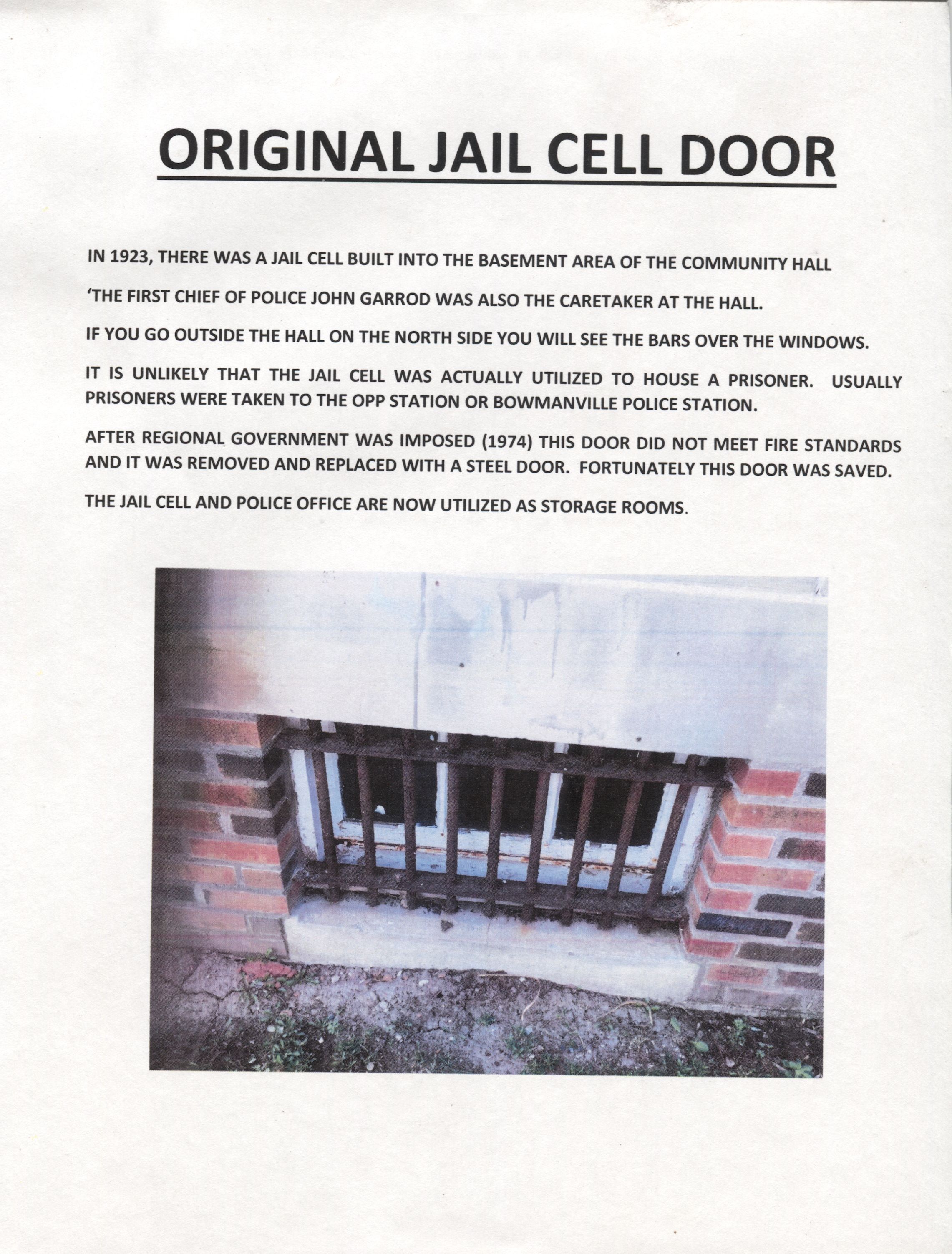 Newcastle Community Hall Centennial Display Photo: A document titled "Original Jail Cell Door," describing a jail cell built in 1923 in the basement of a community hall, overseen by the first chief of police, John Garrod. It mentions bars visible from outside the hall and notes that the cell was rarely used to house prisoners, who were instead taken to OPP or Bowmanville Police Station. After 1974, due to fire standard issues, the door was replaced with a steel one, though the original was preserved.