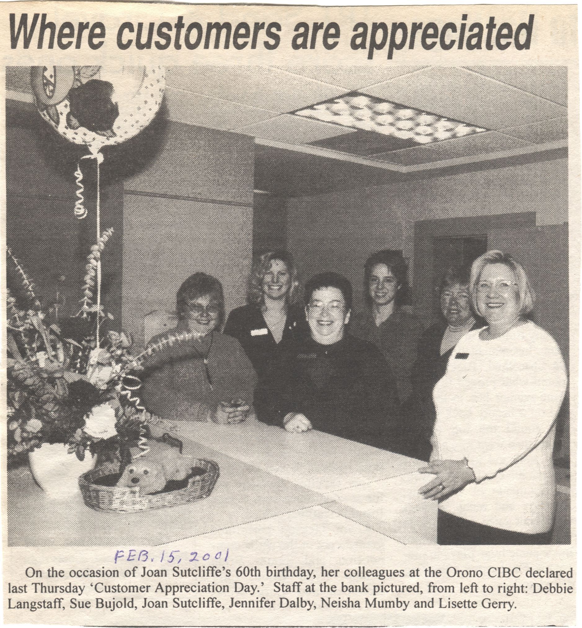 Orono CIBC Customer Appreciation Day Newspaper Article: A newspaper clipping with a black and white image which shows a group of six women standing behind a counter, smiling, in celebration of "Customer Appreciation Day" at Orono CIBC, in honor of Joan Sutcliffe's 60th birthday. A basket with flowers and a balloon sits on the counter, contributing to the festive atmosphere. The women, identified as Debbie Langstaff, Sue Bujold, Joan Sutcliffe, Jennifer Dalby, Neisha Mumby, and Lisette Gerry, are all wearing nametags.