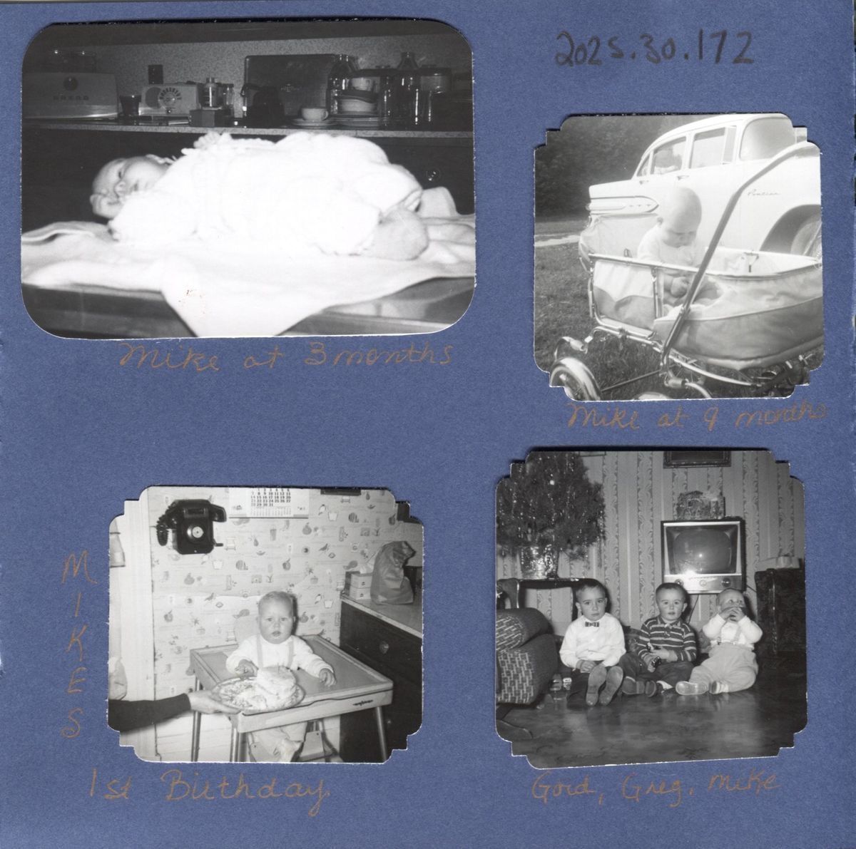 Photos retrieved from the Wade family photo album that are stuck to the page.: The image features a collage of black and white photographs laid out on blue paper with orange pen captioning each photo, and it's displaying a baby's early years, including milestones like first birthday, months old, and a moment in a pram outside, in the bottom right, there are two other young boys sat with the same baby.