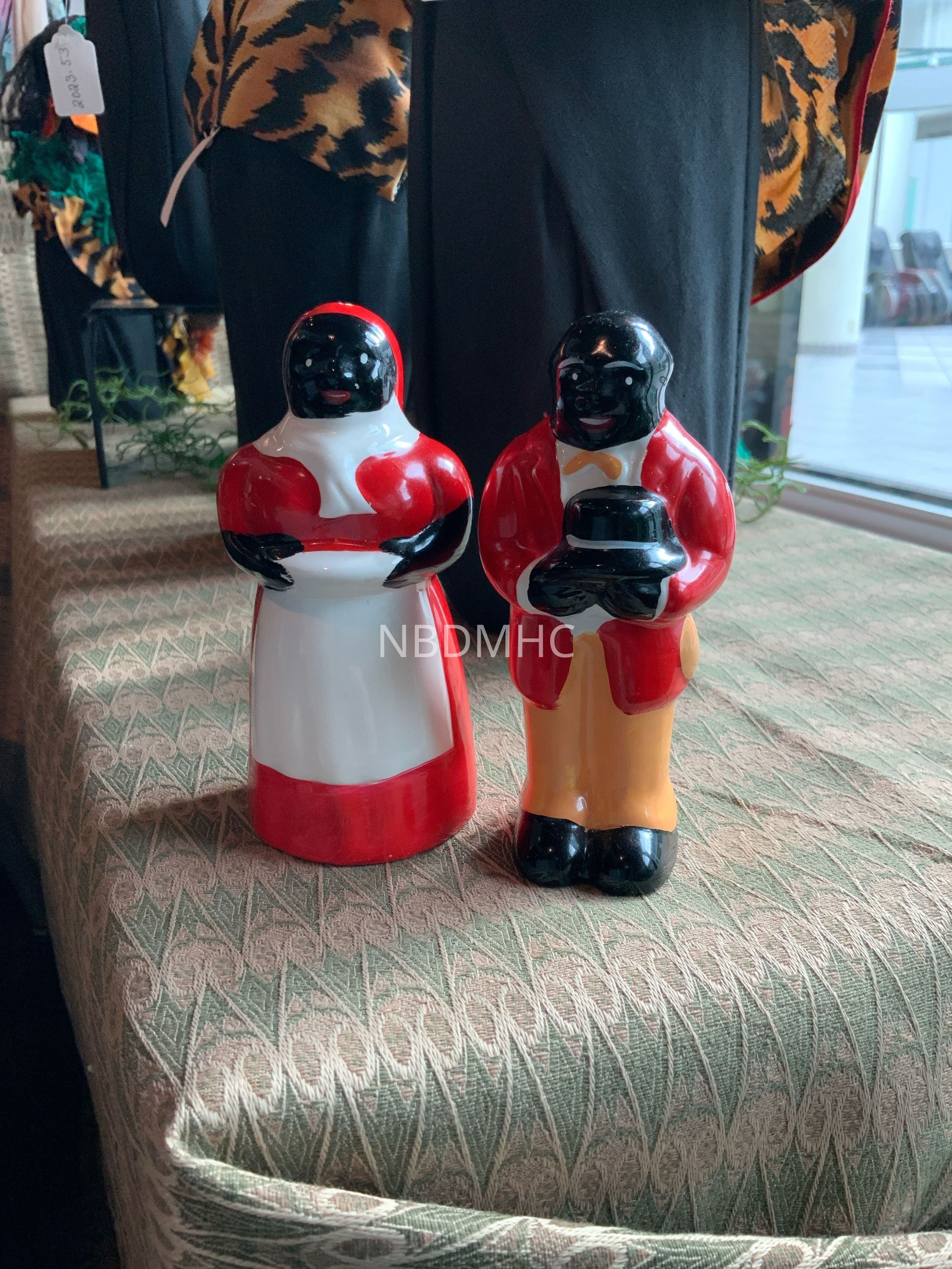 **Title: Vintage Ceramic Couple Figurines**
**Date: Mid-20th Century**
These ceramic figurines, depicting a couple dressed in traditional attire, showcase a style prevalent in mid-20th-century décor. The figures are adorned in vibrant red, white, and black, holding a cake and a bowl. Such pieces were common in domestic spaces, reflecting cultural aesthetics and social dynamics of the era. This set is a poignant reminder of the decorative arts from a specific historical context, inviting reflection on