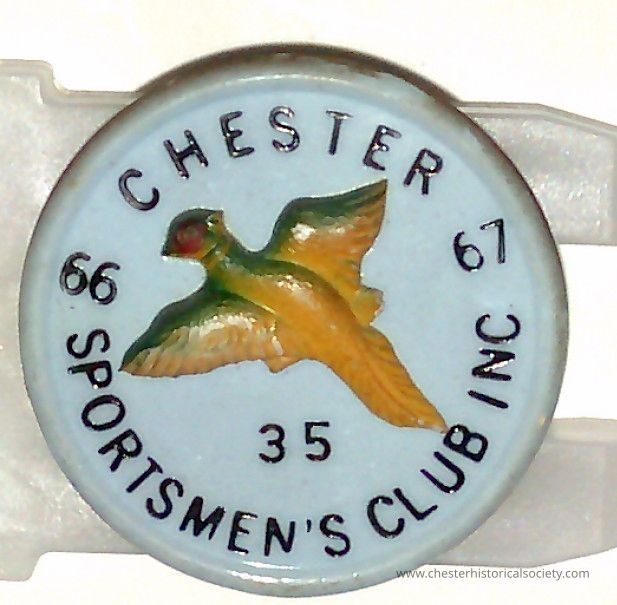 1966-67 Chester Sportsmen Club pin #35: The image shows a circular plastic pin #35 with a light blue background featuring an illustration of a bird in flight positioned centrally. Surrounding the bird, the text reads "CHESTER SPORTSMEN'S CLUB INC," with the numbers "66" and "67" positioned on either side of the bird. Below the bird, the number "35" is printed.