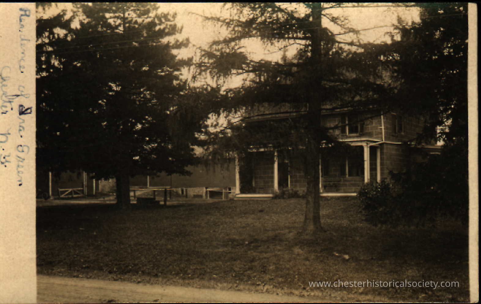 Residence of Ira Green: This monochrome photo postcard depicts a quaint, two-story stone house nestled among mature trees, with its distinctive features including a wraparound porch and stonework facade. Known as the Colvill Carpenter House, the house is believed to have been built as early as c. 1760. It underwent a raising of its roofline in 1809, probably with the intention of providing room for a full second story. A datestone reading "RA 1805 may well refer to a carpenter or mason who worked on the expansion. At the time of this photo it was the farmhouse of Ira Green, on the Washingtonville Road.