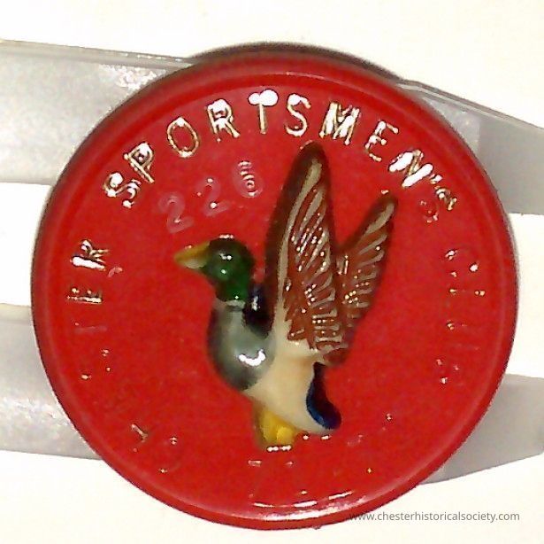 Chester Sportsmen Club pin #226 - 1971-72: The image shows a circular red badge with raised lettering around the edge that reads "Chester Sportsmen Club" for 1971-72 and # "226." In the center, there's a detailed, three-dimensional depiction of a mallard duck, with vibrant colors including green on the head, a white neck ring, and a yellow beak. The duck is positioned with wings raised as if preparing for flight, adding a sense of movement and dynamism to the design.