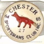 1964-65 Chester Sportsmen Club pin #27: The image shows a round plastic pin #27 with a beige background and black text encircling a detailed depiction of a red fox in the center. The text reads "CHESTER SPORTSMANS CLUB INC." indicating the name and likely the location or affiliation of this organization, as well as the number “27” at the bottom center, which may signify a member's number or a specific designation within the club.