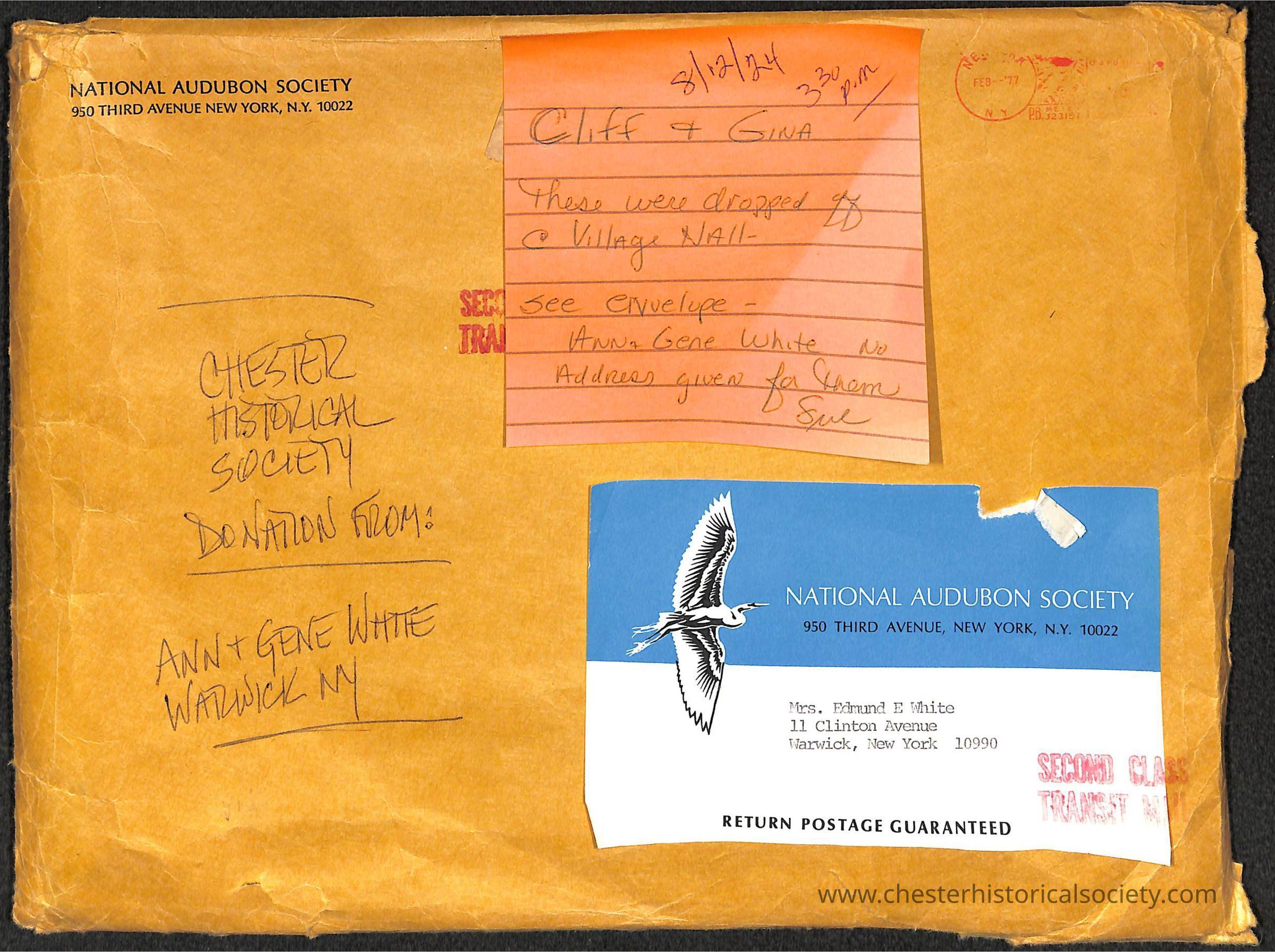 The image displays a worn-out package labeled with multiple annotations and addresses. The upper left portion features the heading "NATIONAL AUDUBON SOCIETY 950 THIRD AVENUE NEW YORK, N.Y. 10022" stamped in black ink on a weathered orange envelope. Below this, "CHESTER HISTORICAL SOCIETY DONATION FROM:" is handwritten with "ANN + GENE WHITE WARWICK NY" scribbled underneath. A torn blue envelope overlaid on the right side bears a white printed image of a bird in flight, a logo of the National Audubon Society, and has a typewritten address: "Mrs. Edmund E White, 11 Clinton Avenue, Warwick, New York 10990." Additionally, an orange sticky note affixed to the upper right portion contains handwritten information about the documents inside, naming "Cliff & Gina" and mentioning that these were dropped off at Village Hall, instructing to see the envelope for more details