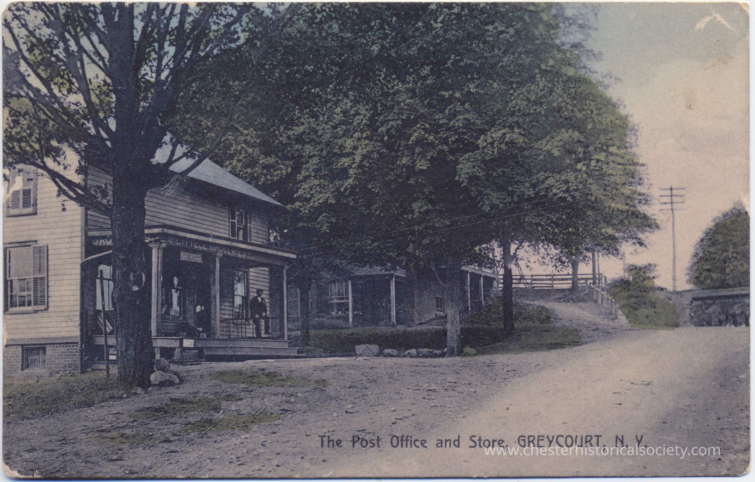 Greycourt Post Office and General Store, Greycourt, N. Y.: This colorized photo postcard depicts an early 20th-century scene showing Edward G. Littell's store, with post office in Greycourt, New York, characterized by its quaint architecture and rural surroundings, with individuals visible on the porches of the buildings shaded by large trees, and a dirt road prominently leading into the serene setting.