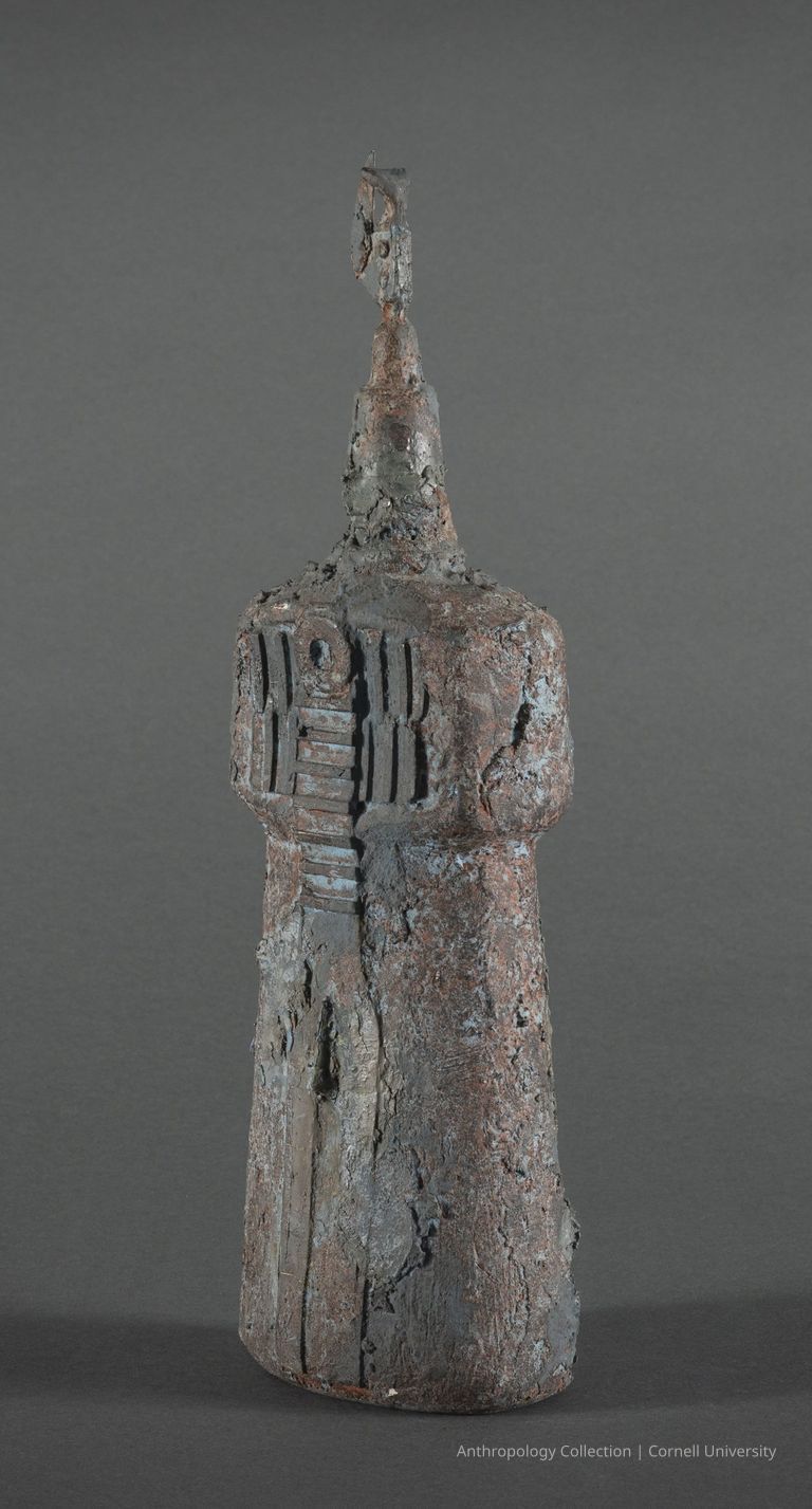 TRALLIB (Oil Container) | 1969 | Photo by Ann Cady, 2024 | ©2025 Cornell University — Female orientation: The image shows a cylindrical weathered object with a corroded, gray metallic surface, female genitalia and breast area, pointed head and a distinct finial top.