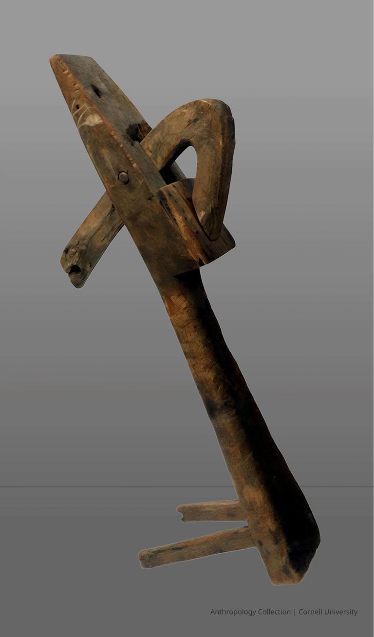 EARLY ICON OF AAR-TENN | circa 1965 | ©2026 Norman Daly Art — The image depicts a rustic carved wooden object featuring a prominent curved element intersecting a vertical structure, possibly part of a traditional or cultural artifact, set against a simple gray background which highlights the texture and grain of the wood.