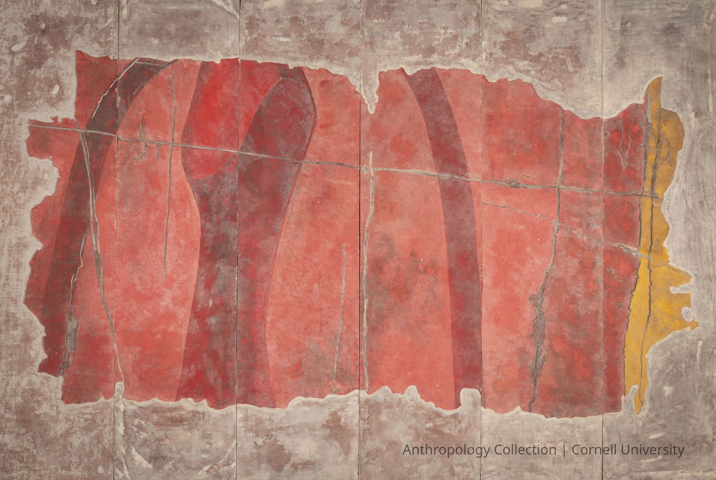 FRAGMENT OF WALL PAINTING FROM TEMPLE OF PHALLOS AT TROLYDOS | circa 1966-71 | Photo by Ann Cady, 2024 | ©2026 Norman Daly Art: Photo-An ancient fresco composed of vivid red and yellow hues on a weathered background, suggesting age and historical significance. The artifact has areas where the paint appears to have faded or chipped, revealing a timeworn texture. Multiple vertical cracks run across the fresco, dividing it into panel-like sections, enhancing its rustic and antiquated appearance. The bold red areas are interspersed with softer shadow-like darker shades, adding depth and dimension to the work, with a small section of yellow on the right.